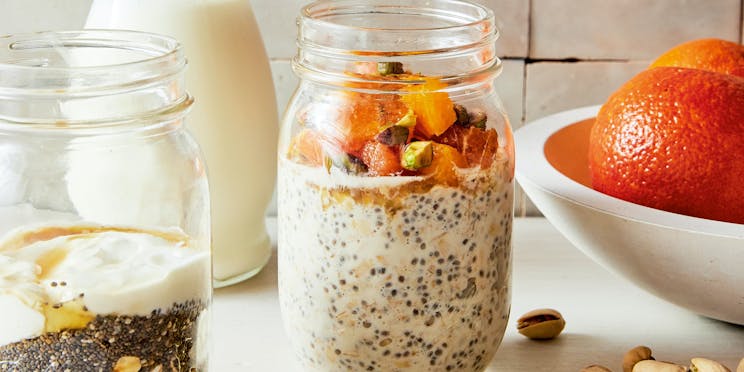 Front view of overnight oats in a jar, with orange and pistachio topped.